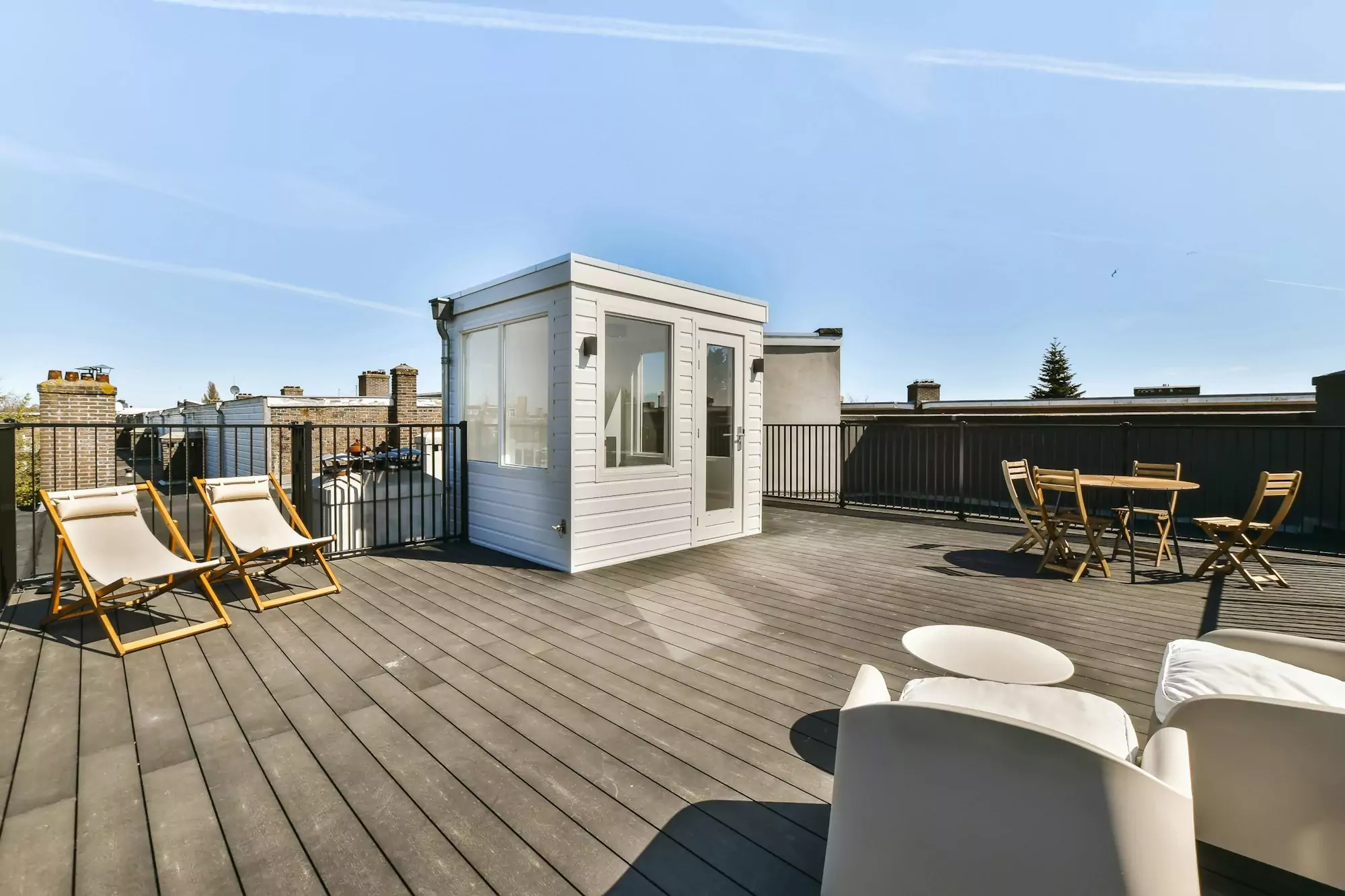 a rooftop deck with chairs and a small shed on