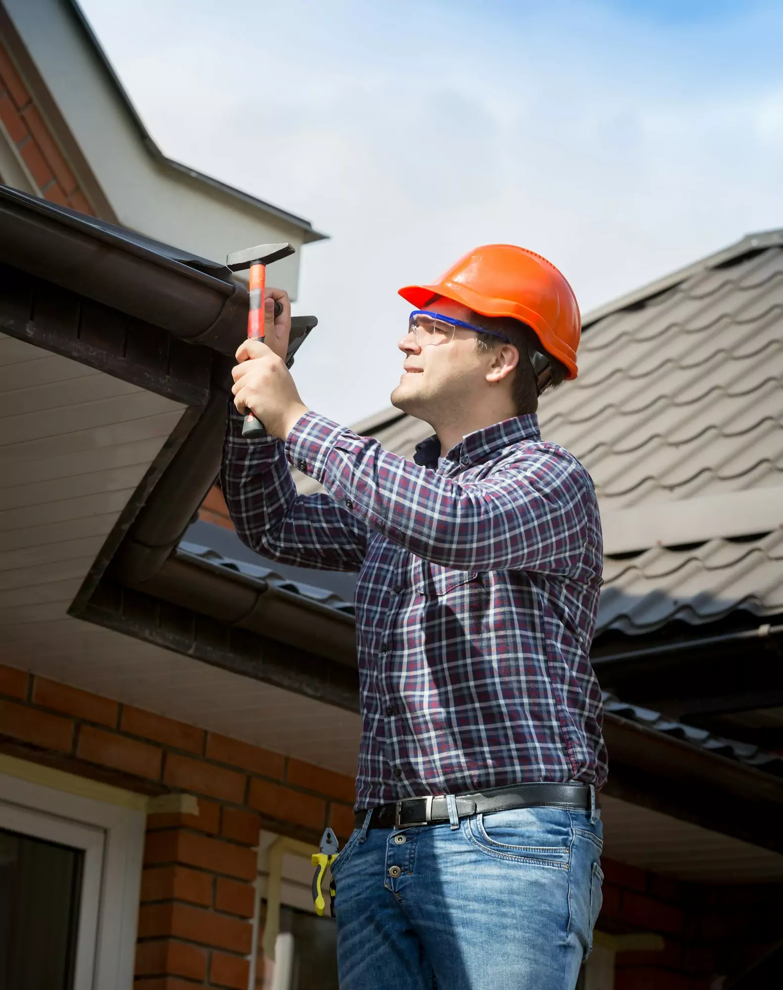 young handyman repairing house roof with nails and hammer